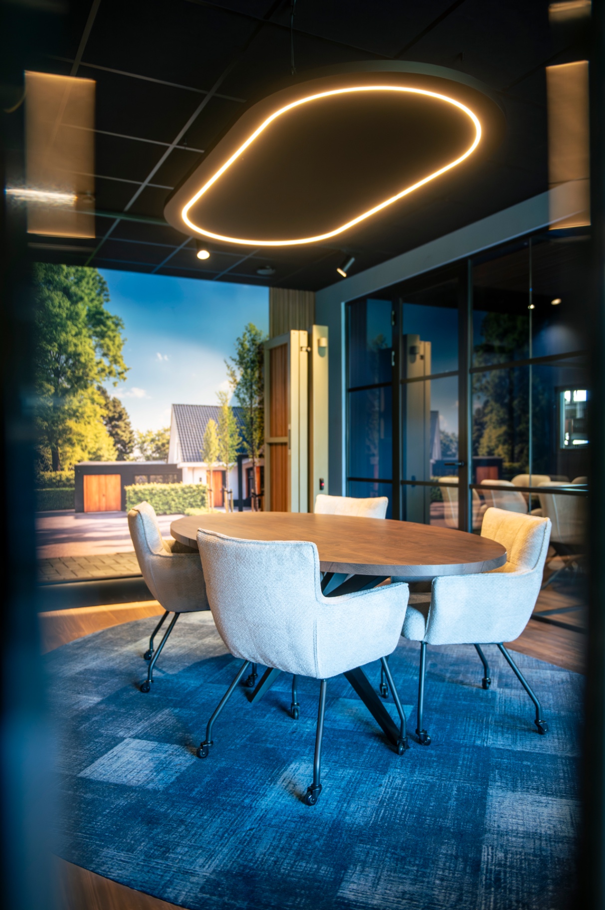 Vergaderruimte met ronde tafel, verlichte plafondring en fotobehang van een tuin