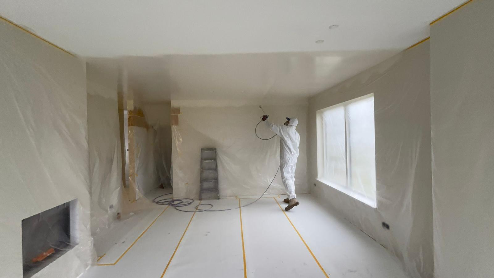 Vakman die een plafond met latex spuit
